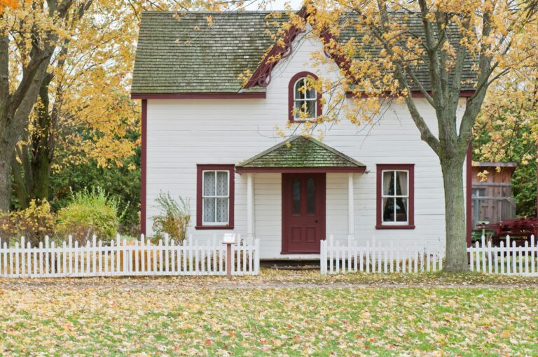 Picturesque traditional house with autumn foliage and a white picket fence in London, Ontario.